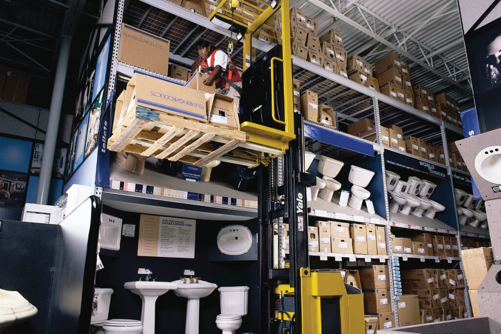 Indoor aisle forklift - stock person in home center working from lift truck to load / unload shelving.