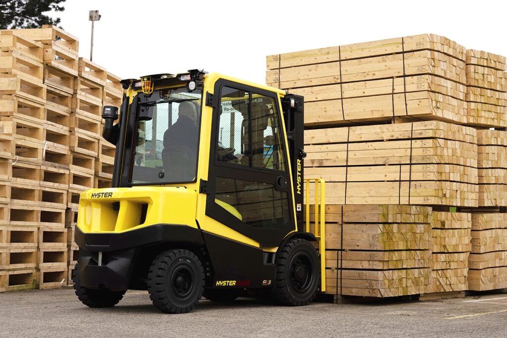 Hyster forklift moving a bunk of lumber in an outdoor yard